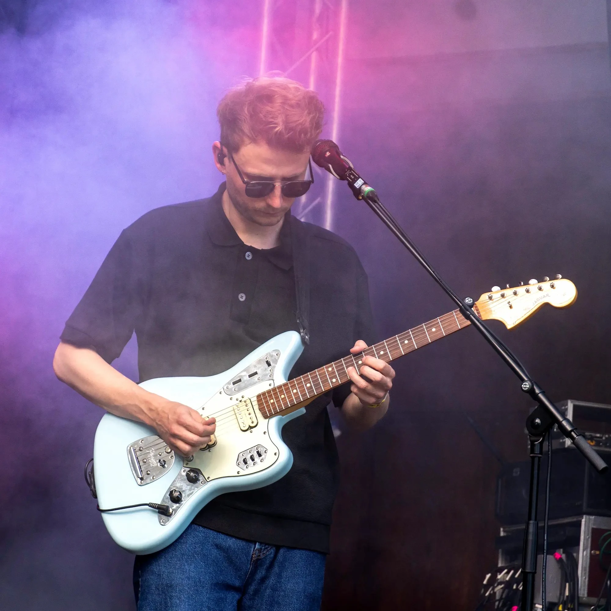 Gitarrist spielt E-Gitarre auf einer Bühne im bunten Nebellicht.