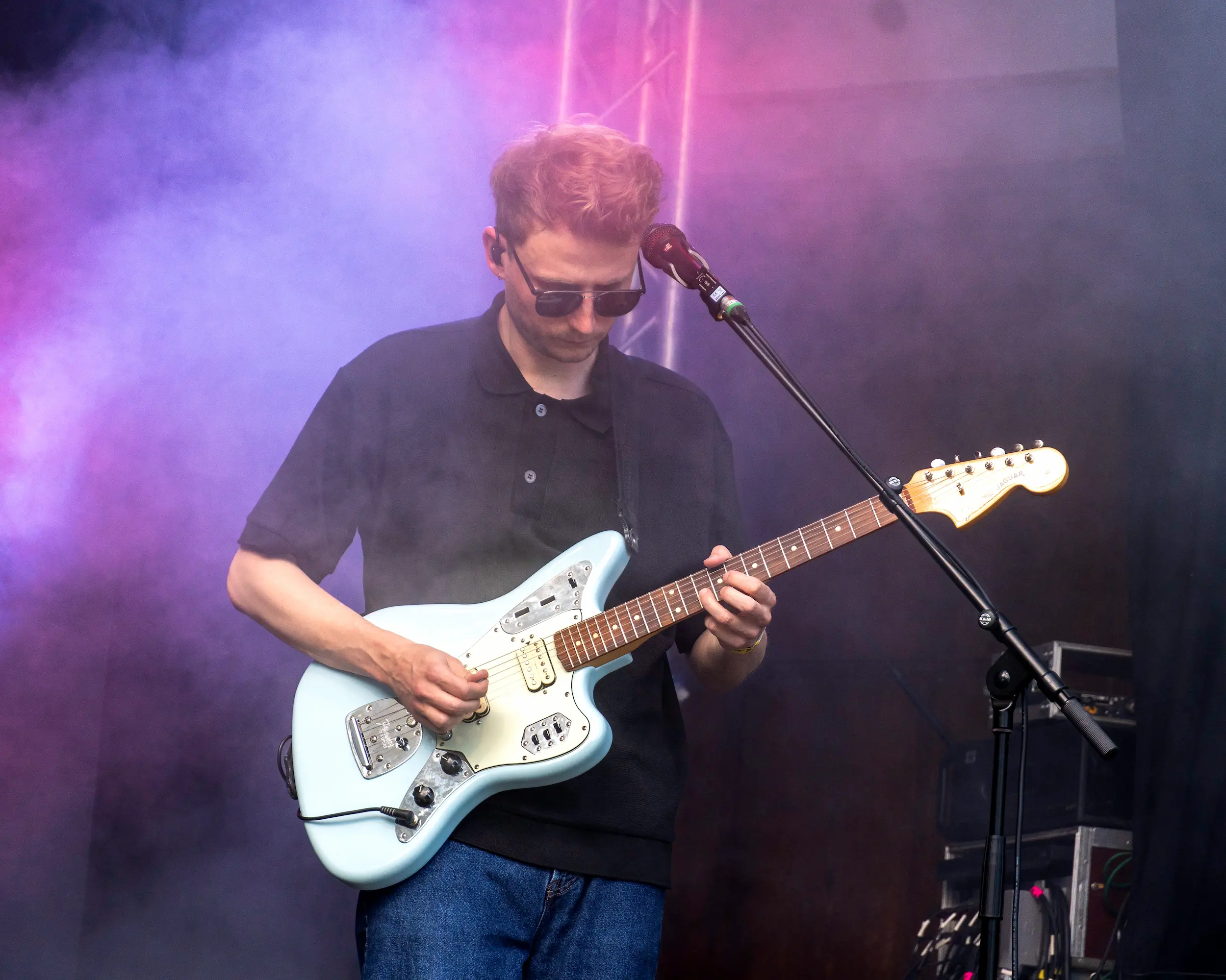 Gitarrist spielt E-Gitarre auf einer Bühne im bunten Nebellicht.